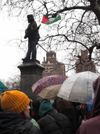 A protester waves a Palestinian flag from the Giuseppe Garibaldi statue in Washington Square Park.