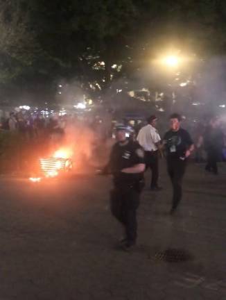 <b>Police in riot gear at Union Sq. Park on May 30, 2020, as a trash can lit on fire by protestors burns.</b>