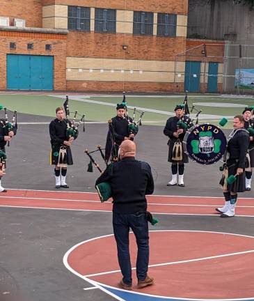 The NYPD Emerald Society Pipes and Drums warm up prior to the Mass in the playground of PS 48, named for their fallen comrade, Michael Buczek.