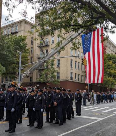 An FDNY truck hung a huge American flag from its ladder as friends and family who have turned up for the annual memorial service for the two police officers marched toward St. Elizabeth’s Church as they have done for 35 years. Photo: Brian Berger