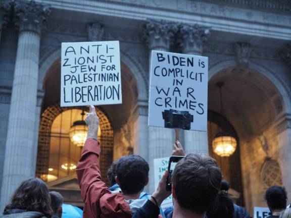 Pro-Palestine protesters hold up signs outside of the main entrance of the New York Public Library flagship location at a rally on Friday, Oct. 20.