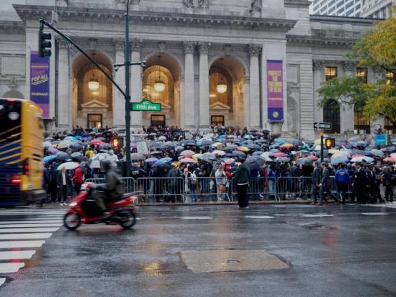 A crowd of protesters gather in heavy rain outside of the New York Public Library on Fifth Ave., spilling onto the sidewalk.