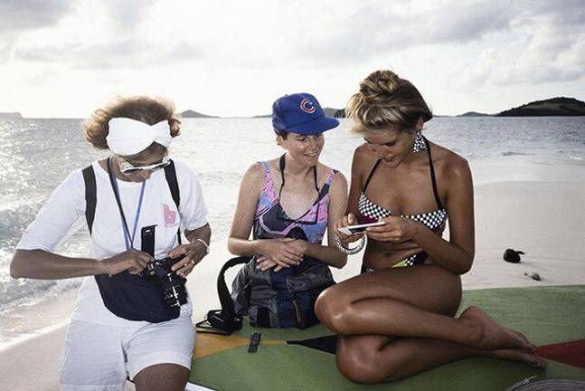 Director Creates Filmic Ode to Legendary Sports Illustrated Swimsuit Editor Model Judit Masco looks at a polaroid during a Sports Illustrated Swimsuit Issue shoot on Palm Island in Saint Vincent and the Grenadines in the fall of 1989. Jule Campbell loads film into her camera as Jule's assistant Christine Walker looks on.