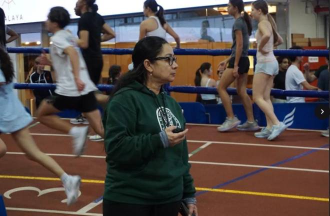 Coach Olga Ladino checks the clock as the girls track team at St. Vincent Ferrer trains at the 168th St. Armory. Last year, the school qualified for the NYS championship for the first time ever. Photo: Gladys Gerbaud
