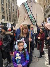 Kimberly Schiller carries a shirtwaist banner with the name of one of the 146 people who died in the Triangle Shirtwaist Factory Fire in 1911 in the biggest fire tragedy in the city’s history. Her daughter Anna Lee carries three white roses. The victims were mostly poor Jewish and Italian immigrants.<b> Photo: Keith J. Kelly</b>