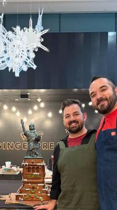 Couple Ricky Rotandi (left) and César Aldrete, winners of Season 36 of the reality TV show “The Amazing Race,” show off their award-winning contribution to MCNY’s 2025 gingerbread bake-off.
