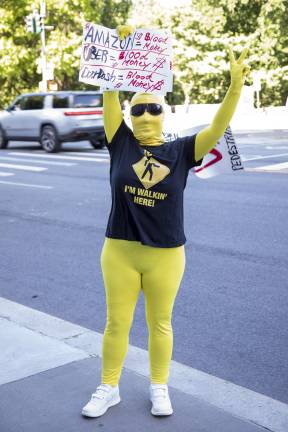 A protester holds a sign criticizing Amazon, Uber and DoorDash during a demonstration outside Transportation Alternatives’ annual fundraiser at the New-York Historical Society.