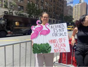 Albania Is Not For Sale: Hands Off Sazan and Narta reads a protest sign adorned with flamingos.