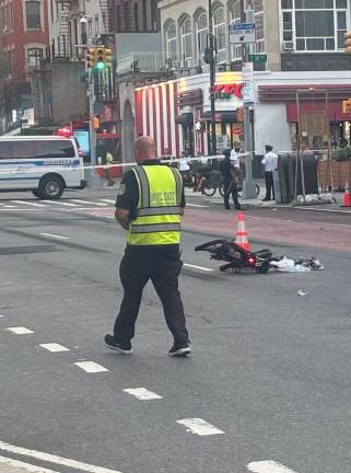 A crumpled e-bike sits in the middle of Second Avenue—with its rear red light still flashing—after a 65-year-old biker hit his head after a collision with a Nissan driven by an unlicensed driver. The driver fled but was arrested two hours later.