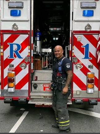FDNY Firefighter Aaron Clark besides a Rescue 1 truck.