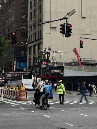 Two men run a red light on an E-Bike as a Traffic Officer faces the other way on intersection of W. 34th and 8th Ave.