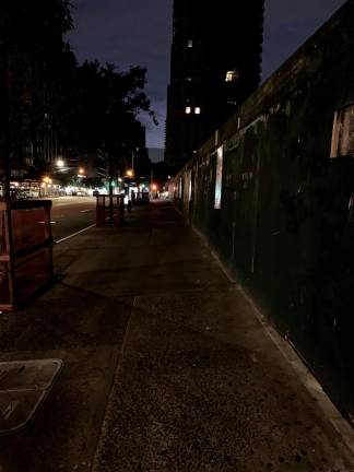 A view looking north up the east side of First Ave. from the corner of East 79th St. The entire darkened block near an Extell construction fence is forbidding and spectral in appearance, and though it's only 9 p.m., not a single pedestrian is in sight.