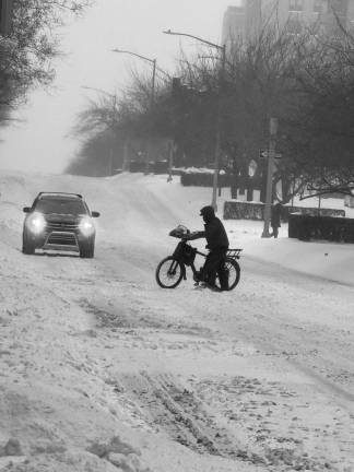 Another delivery worker crosses the street as snow falls heavily on Fifth Ave. on the Upper East Side