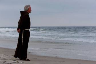 In this July 17, 2000 file photo, Father Mychal Judge, a chaplain with the New York City Fire Department, stands at the shore before a service where 230 candles were lit for the July 17, 1996 victims of TWA Flight 800, at Smith Point Park in Shirley, N.Y. Judge left a uniquely complex legacy that continues to evolve 20 years after his death.