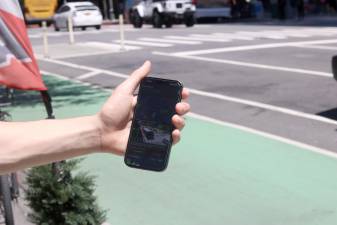 ParkSignal NYC detects open street parking spots. Eighteen-year-old Theo Darringer holds his phone in front of the free spot the app says is open.
