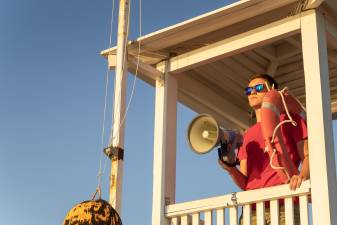 The lifeguard is watching the beach from the surveillance tower.