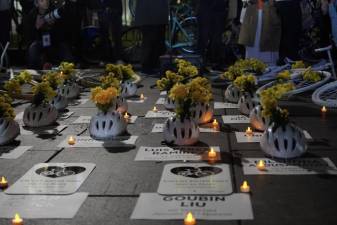 White helmets surrounded by white bikes, with the names of cyclists who died in traffic incidents this year, on the ground in front of City Hall as part of an Oct. 11 rally. There have been 26 cyclist fatalities so far in 2023 — the highest cyclist death toll since 1999.