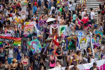 Marchers carry signs of different LGBT+ saints at Pride 2021. Photo: Trish Rooney