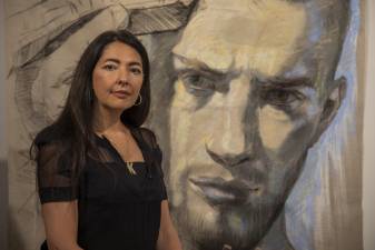 Ukrainian painter Zhenya Gershman stands proudly in front of a portrait she made of a young soldier going off to war in the Russia-Ukrainian war.