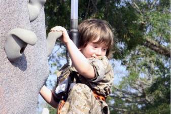 A military child looks back as he makes his way up the rock climbing wall during the first Headquarters and Support Battalion Kids Boot Camp, aboard Marine Corps Base Camp Lejeune.