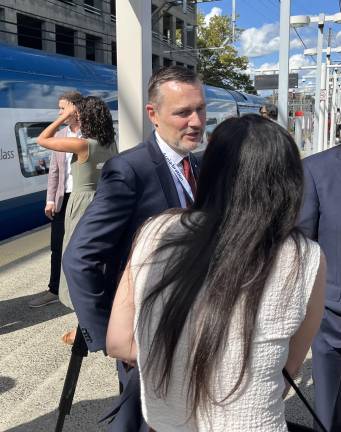 Standing near the Aug. 27 Preview Train in New Haven, Amtrak president Roger Harris stops to chat with an invited guest on the platform. The train made longer stops in New Haven and Providence on its way north. Harris rode the train the entire way from Washington DC to Boston, only to return the following morning on the first revenue train to DC.