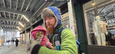 An unhoused individual, Ethan, known locally as “Freckles,” holds his cat “kitty” the day after a city sweep. He says he always returns to the Broadway and W. 75th St. location under a scaffold the minute city officials leave because he prefers to live outside.