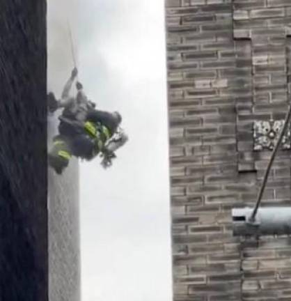 A firefighter rescues a victim from a burning building on St. Nicholas Place in Harlem. Photo: NYPD