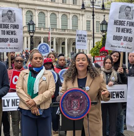 City Council member Carmen De La Rosa at the podium, News Guild president Susan DeCarava in colorful scarf left.