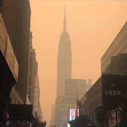 <b>Cars driving on a major cross town street all have headlights on to try to pierce through the yellow fog that is enveloping the city. The haze nearly obscures the Empire State Building a mere three blocks away at mid-day on June 7.</b> Photo: Keith J. Kelly