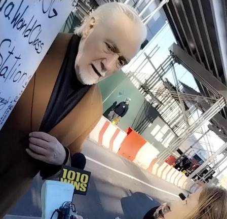 A protestor who is against knocking down buildings around Penn Station is interviewed by radio station WINS 1010 AM outside the Hudson Rail Yards, where Governor Kathy Hochul, Sen. Chuck Schumer and others were speaking at the groundbreaking of the Gateway rail tunnel project.