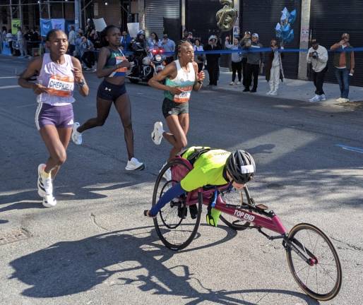 The lead women blocked by a lagging wheelchair racer on Rider Avenue in the Bronx.