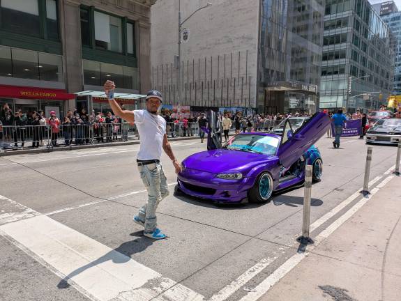 A custom-car driver takes a selfie before rolling in the line of march at the AAPI Parade.