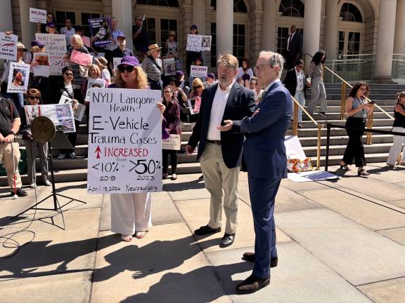 Janet Schroeder (left), president of the NYC E-Vehicle Safety Alliance, speaks with attorney Jim Walden (right), chairman of NYC Common Sense, and Andrew Fine before a June 25 news conference outside City Hall announcing a lawsuit over the city’s e-bike enforcement policy.
