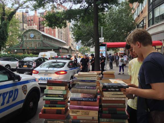 Police officers confer steps from Kirk Davidson's sidewalk book table on Broadway near 73rd Street on July 13, a week after police dismantled several similar tables and impounded thousands of books along that stretch of the avenue. Photo: Richard Khavkine