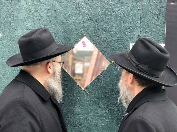 Rabbi Shlomo Kugel, at left, director and co-founder of the Chabad of the West Side, and Rabbi Meir Ossey, the group's associate director, peer through a hole in the construction fence at the site of Chabad's future home on West 96th Street.&#160;Photo: Chabad of the West Side&#160;