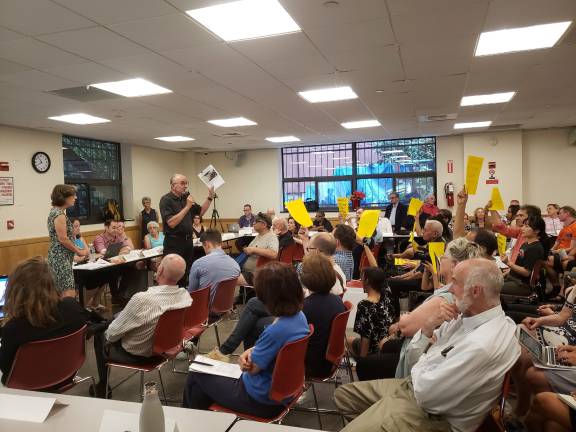 Some residents at the meeting waved yelllow signs reading &quot;Board 7 do the right thing.&quot; Photo: Jason Cohen