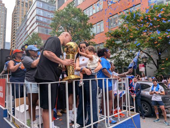 Baby Jordyn Brunson in her moms arms, touches trophy held by her grandpa, Rick Brunson.