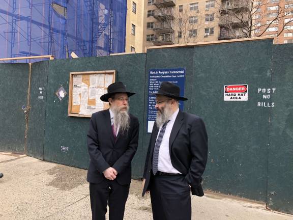 Rabbi Meir Ossey, at left, associate director of the Chabad of the West Side, and Rabbi Shlomo Kugel, the group&#x2019;s director and co-founder, stand before a construction fence on West 96th Street where Chabad is developing its new five-story home, complete with two synagogues and a preschool for 150 kids.&#xa0;Photo: Chabad of the West Side&#xa0;