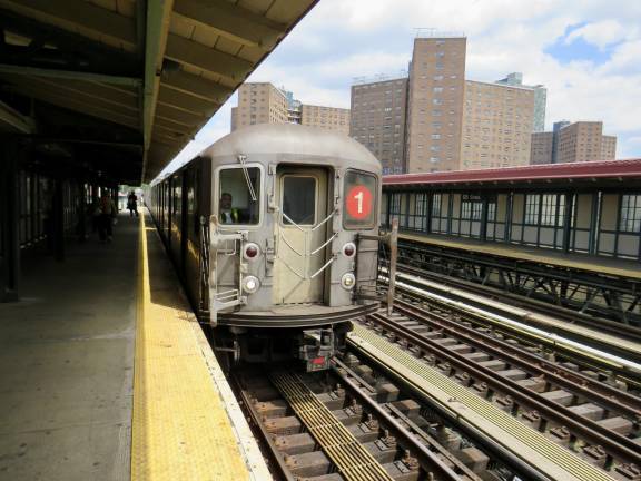 A downtown #1 train pulling into the West 125th Street &amp; Broadway station. The NYCHA Manhattanville Houses are to the right.