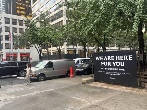 A sign at St. Bart’s Church, directly across the street from the scene of the mass shooting on July 28, offers comfort. A flag outside 345 Park Ave. can be seen flying at half-staff.