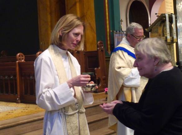 The Rev. Katharine Flexer gives communion to a parishioner. Photo by William Mathis.