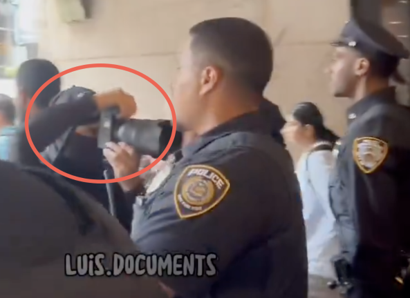 Unknown photographer in full sheisty mask, while police stand by unmasked.