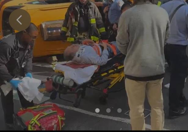 Firefighters and EMS workers place the injured man on a gurney after a taxi cab flipped over on Oct. 22.