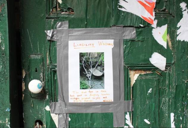 <b>An angry resident posted a hand made “liability warning” sign on the abandoned building at 131 W. 70th alerting people to the dangers from falling branches from a dead tree in the back yard.</b> Photo: Ethan Geringer-Sameth