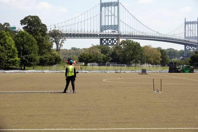 A construction worker standing on a playing field on Randall’s Island.