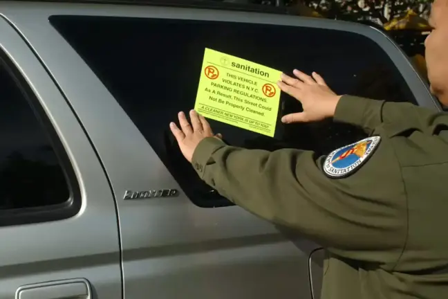 The NY Department of Sanitation has started affixing adhesive stickers to cars violating street cleaning parking rules again, bringing back a practice that had been prohibited since 2011 before a City Council vote in June 2026 allowed the Department of Sanitation to resume the practice starting in August.
