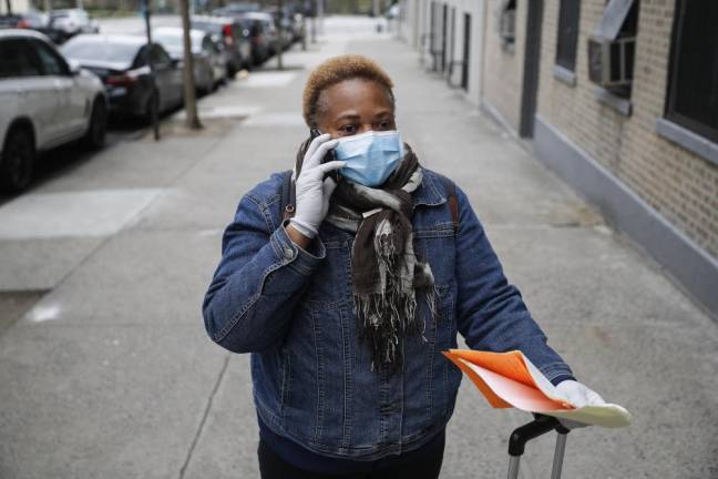 Ruth Caballero, a nurse with The Visiting Nurse Service of New York, speaks with a patient's doctor after a home visit as she makes her rounds in upper Manhattan, Thursday, April 23, 2020.