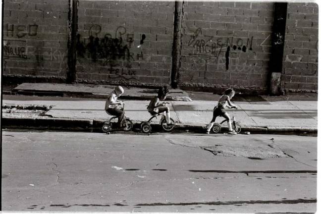 Three kids ride their tricycles down a Lower East Side street (1980). Photo courtesy of Alex Harsley