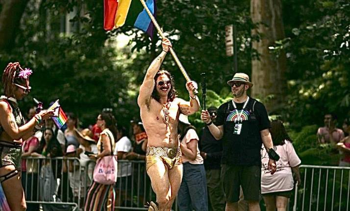 Muscle bound rainbow flag waving Adonis in gold satin hot pants at Heritage of Pride parade.