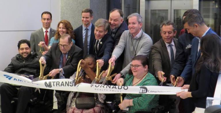 Disability activist Emily Ladua (green jacket, near center) joins the CEO of Amtrak and Vornado Realty Trust and local politicians in cutting a symbolic ribbon to reopen the main Seventh Ave. entrance to Penn Station, which for the first time in its history will be ADA compatible. Photo: Ralph Spielman